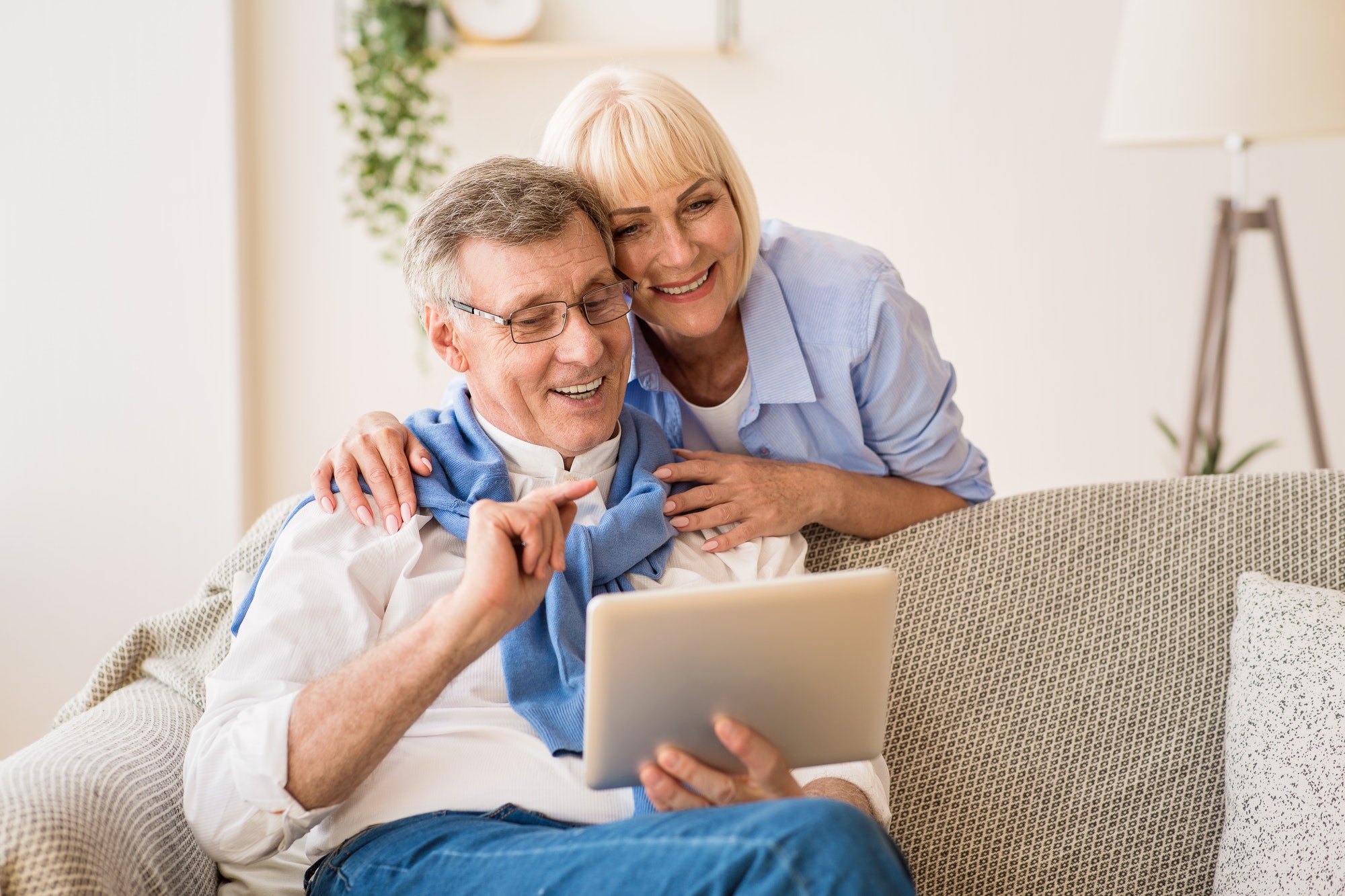 Happy pensioners using tablet, relaxing on rug