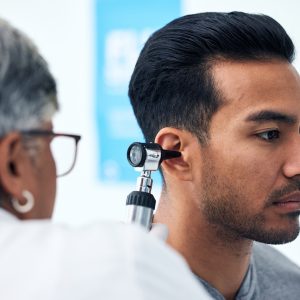 Ear check, man and clinic doctor with patient consultation for hearing and wellness at hospital. Se